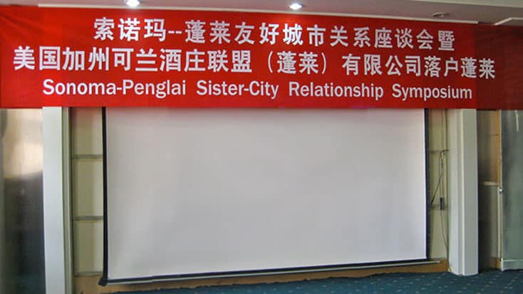 A red banner with Chinese writing commemorating the Sonoma-Penglai Sister City Relationship Symposium