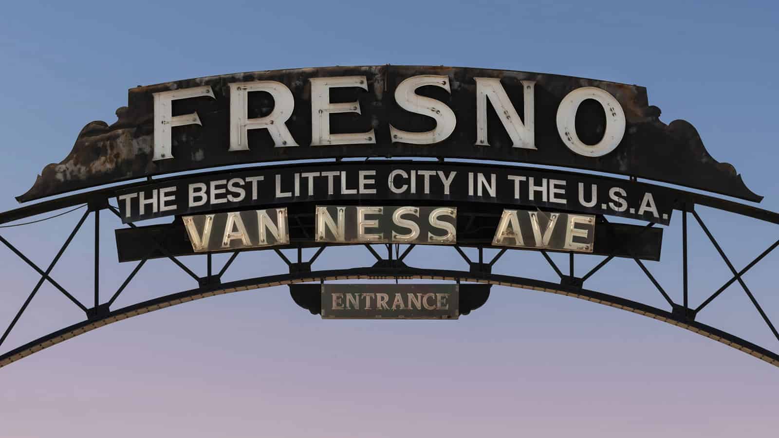 Archway street sign reading "Fresno The Best Little City in the USA, Van Ness Ave, Entrance"