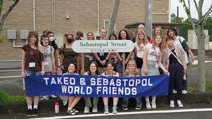 A group of students holding a banner that says Takeo and Sebastopol World Friends.