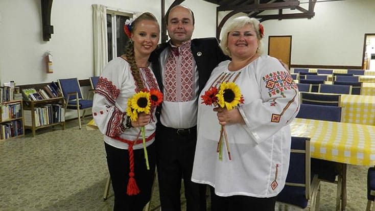 Three people in traditional ukrainian clothing posing for a photo.