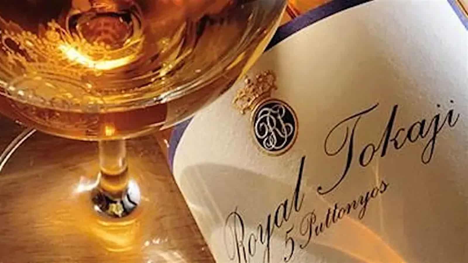 Close-up of a glass filled with golden wine, next to a bottle labeled "Royal Tokaji 5 Puttonyos.