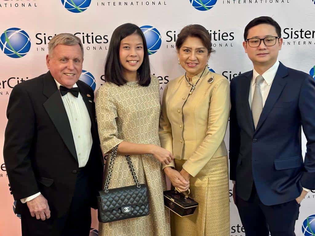 Four people in formal attire standing side by side at a Sister Cities International event backdrop.