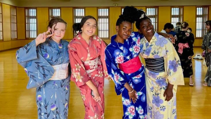 Four people from the Marin Student Delegation, wearing colorful yukatas, pose together and smile in a spacious, well-lit room with wooden floors and papered windows during their student travel to Sakaide.